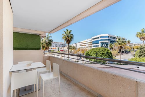 Modern terrace with city views, white dining furniture, and artificial green wall in Marbella apartment