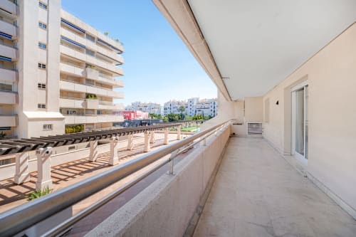 Spacious terrace with city views in Marbella apartment, featuring lounge chairs and overlooking Marina Banus neighborhood