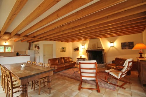 Spacious open-plan cottage living area with wooden beams, fireplace, and rustic furnishings at Domaine de Bort near Limoges