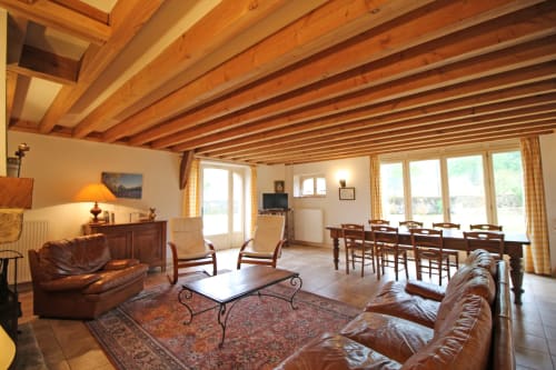 Spacious cottage living room with wooden beam ceiling, leather seating, and dining area at Domaine de Bort near Limoges