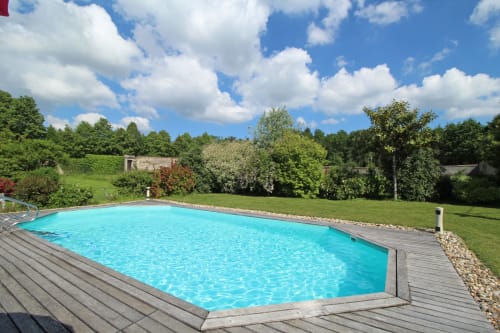 Turquoise swimming pool with wooden deck at Domaine de Bort cottage rental near Limoges, France