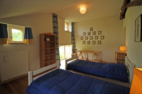 Twin bedroom with blue duvets at Domaine de Bort gîte near Limoges, featuring wooden furniture and countryside views