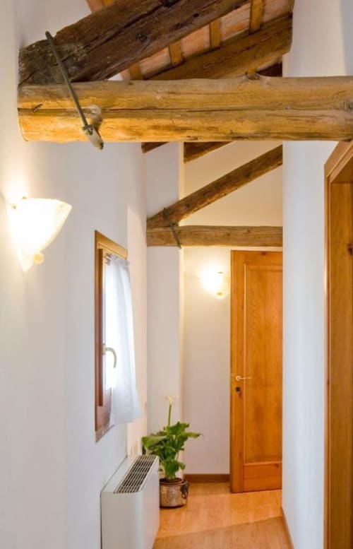 Corridoio rustico con travi in legno a vista presso l'Agriturismo Villa Mocenigo a Mirano, Italia, con porte e pavimenti in legno massiccio
