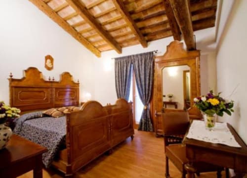 Camera da letto elegante con travi a vista all'Agriturismo Villa Mocenigo, arredata con mobili antichi e pavimenti in legno