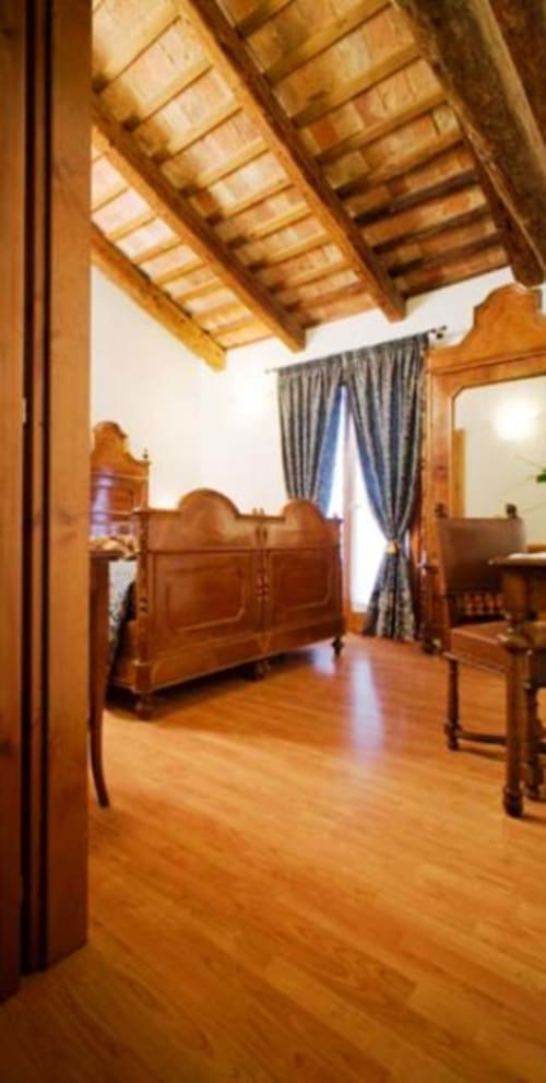 Camera da letto rustica ad Agriturismo Villa Mocenigo con soffitto a travi a vista, pavimenti in legno massello e mobili antichi