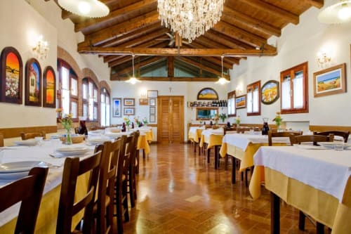 Elegante sala da pranzo di Agriturismo Villa Mocenigo a Mirano con travi in legno, lampadari e finestre ad arco