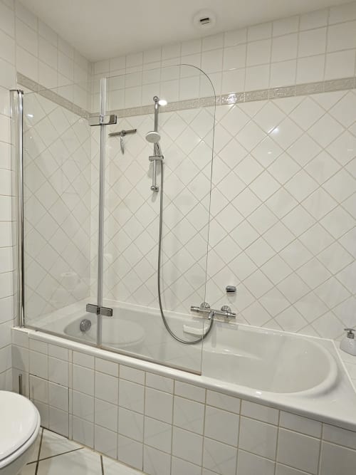 Modern bathroom with white subway tile, glass shower enclosure, curved bathtub, and chrome fixtures at Château de Ribourdin