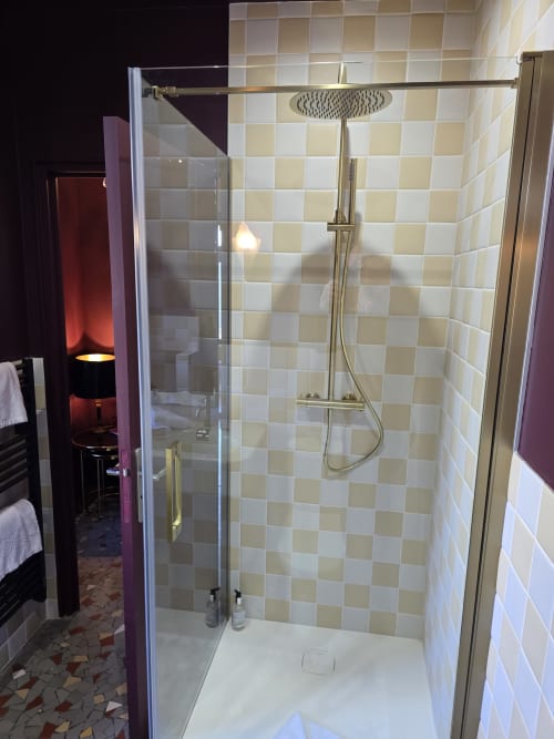 Douche moderne avec pommeau de douche cascade à l'hôtel Le Castel à Bayeux, carrelage à damier crème et blanc