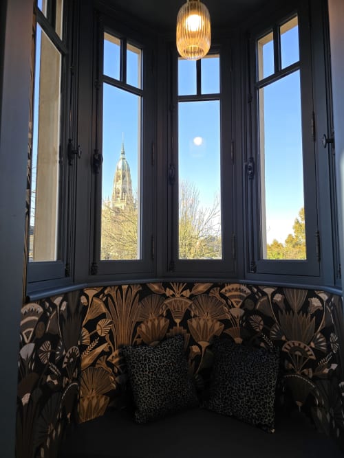 Baie vitrée à cadre noir, papier peint botanique doré ornementé et coussins, vue sur la Cathédrale de Bayeux, Le Castel BnB