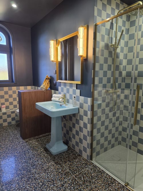 Salle de bain luxueuse du Castel B&B Bayeux avec carrelage à damier, lavabo sur piédestal, robinetterie dorée et douche