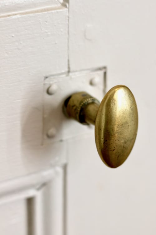 Brass oval door knob on white painted door at Domaine de Bort historic property in Saint-Priest-Taurion