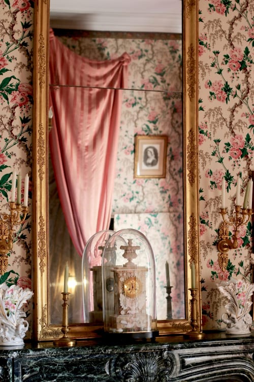 Elegant fireplace mantel with gilt mirror, candelabras, and glass cloche in historic French bedroom at Domaine de Bort