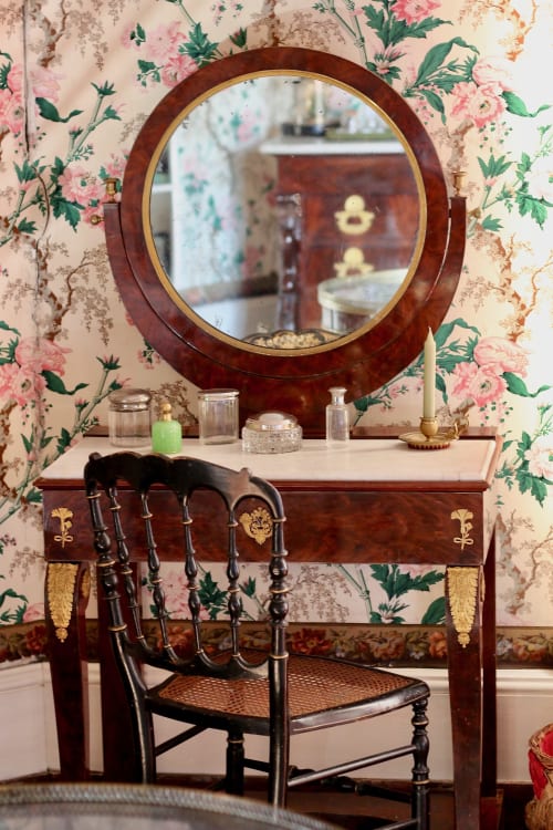 Vintage vanity with round mirror and floral wallpaper in La Chambre des Isles at Domaine de Bort near Limoges