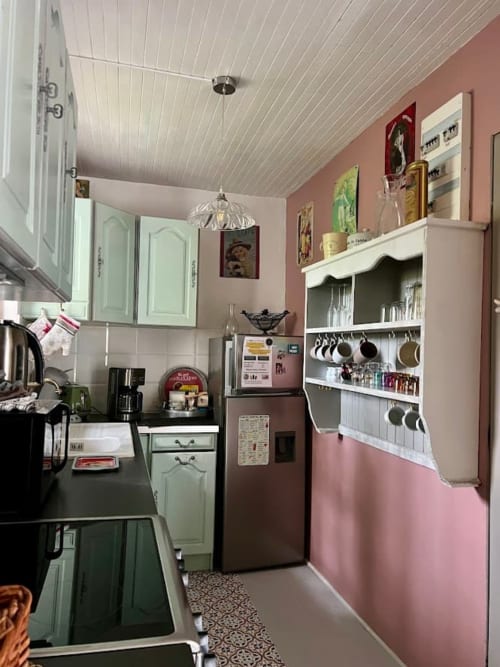Cuisine de charme au Domaine le Manoir avec murs roses, étagères blanches et décoration vintage