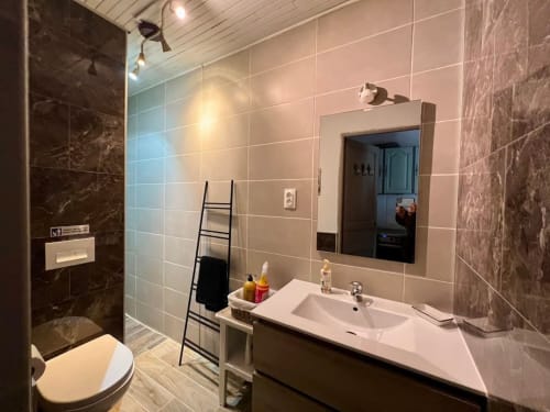 Salle de bain moderne avec lavabo blanc, grand miroir, douche carrelée et toilettes au gîte Domaine le Manoir