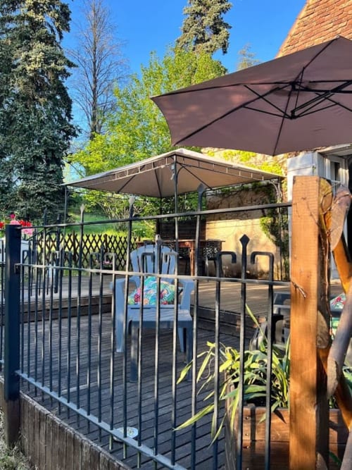 Terrasse extérieure du Domaine le Manoir avec parasols noirs, espace de restauration, balustrade et vue sur le jardin à Fossemagne, France