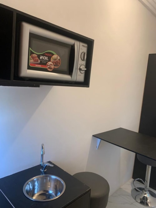 Kitchenette de la Mini-suite F7 à la Résidence hôtelière Ôkèrè Ôburu, Lomé avec micro-ondes, évier et comptoir de repas