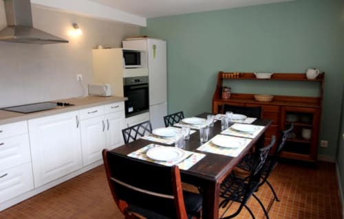Bright kitchen-dining area at Gîte de L'Orangerie with white cabinetry, dining table set for guests