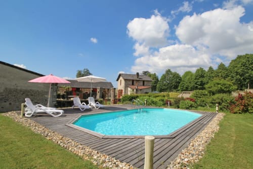 Rectangular turquoise pool with white loungers and pink umbrella at Domaine de Bort gîte near Limoges, France