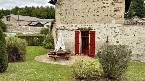 Stone cottage with red shutters and picnic table in garden at Domaine de Bort near Limoges, France