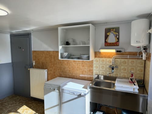 Compact kitchenette in Gîte Le Jardin cottage at Domaine de Bort near Limoges, featuring stove, sink, open shelving and