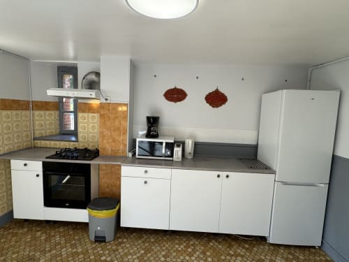 Compact kitchen in Gîte Le Jardin cottage at Domaine de Bort near Limoges with white cabinets, brown tilework, and modern
