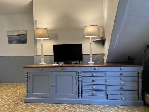 Elegant blue desk with wooden top, twin lamps, and flat-screen TV in cottage bedroom at Domaine de Bort near Limoges