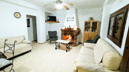 Amplio salón en la villa Casa Rural Ribera del Hueznar, Constantina, con chimenea, cómodos asientos, televisor y techos