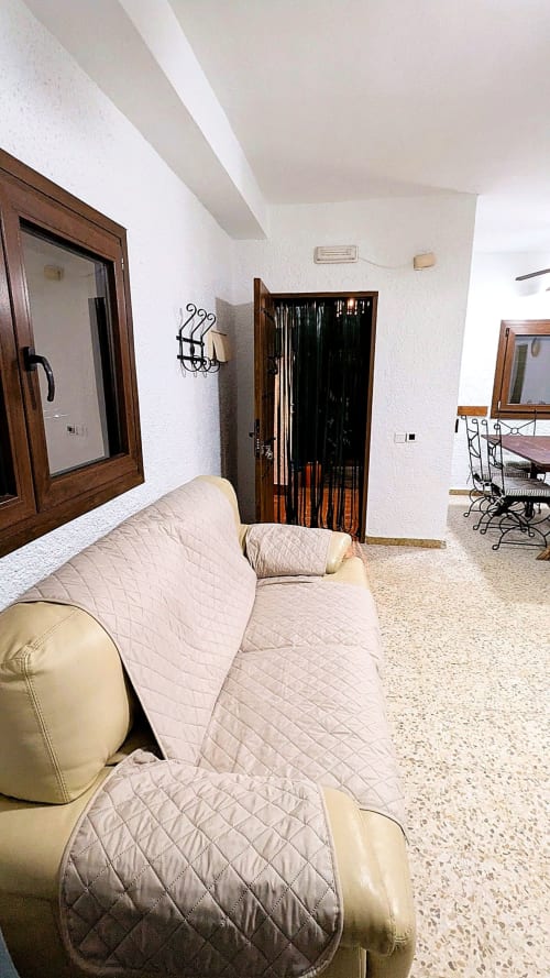 Espacioso salón con sofá beige y manta acolchada en la villa Casa Rural Ribera del Hueznar, Constantina, Cazalla de la Sierra, con decoración blanca