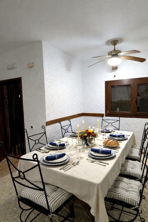 Elegante comedor de la villa Casa Rural Ribera del Hueznar en Sierra Morena de Sevilla, Cazalla de la Sierra Constantina con mesa preparada, servilletas azules y ventilador de techo