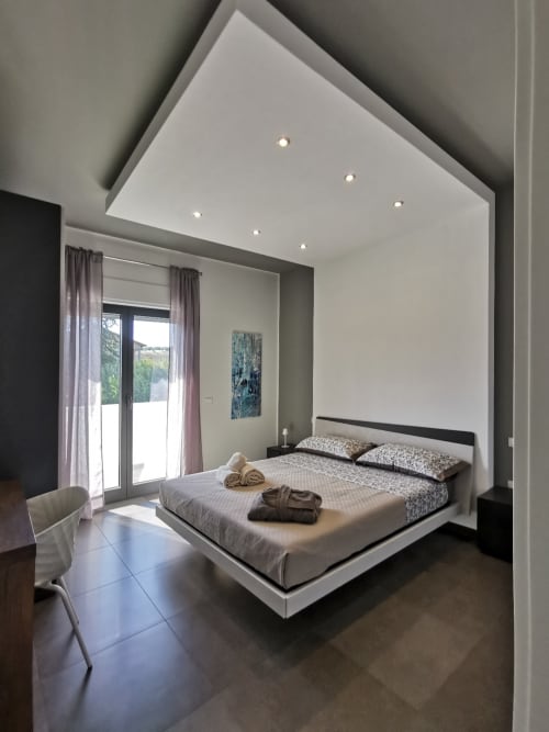 Modern deluxe double bedroom at Green Land Boutique Hotel with platform bed, recessed ceiling lights, and garden views from