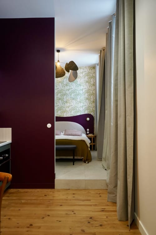 Entrée de chambre à La Maison D'olivier B&B avec porte violette, parquet et lit aux papiers peints tropicaux