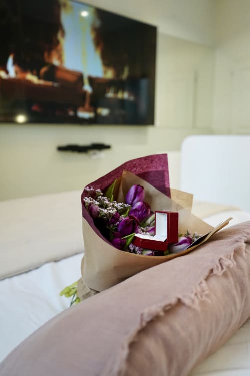 Suite de luxe à La Maison D'olivier avec bouquet de tulipes violettes et boîte à bijoux rouge sur le lit