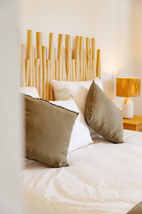 Modern bedroom at Vista Del Mar hotel in Sainte-Anne with bamboo headboard, neutral pillows, and gold lamp