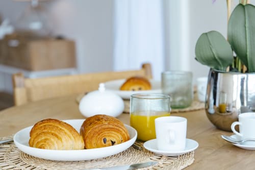 Breakfast table at Vista Del Mar with croissants, orange juice, coffee cup, and potted cactus in Sainte-Anne