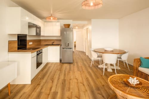 Modern kitchen and dining area at Vista Del Mar in Sainte-Anne with white cabinets, wood countertops, and wooden flooring