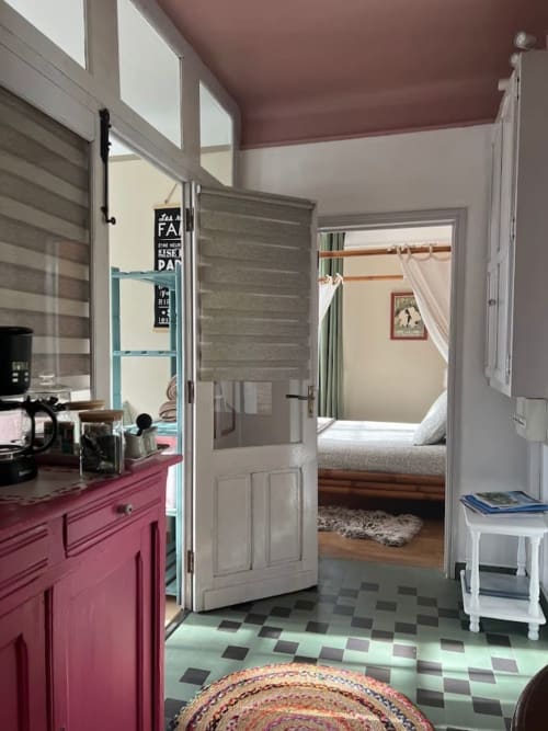 Chambre de gîte moderne avec armoires de cuisine roses, portes blanches et carrelage motifs au Domaine le Manoir
