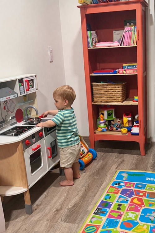 Petit enfant jouant dans la salle de jeux avec cuisine de poupée et bibliothèque rouge, Maison Joséphine, Dordogne