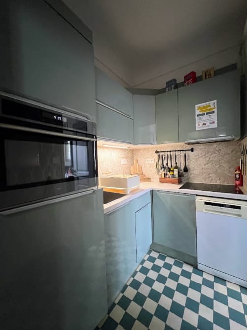 Cuisine moderne du gîte La Maison Joséphine avec meubles gris, four noir, carrelage à damier et rétroéclairage chaleureux