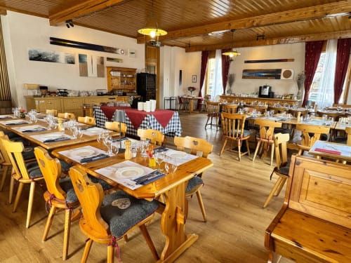 Salle à manger de l'Hôtel La Tour d'Aï à Leysin avec tables en bois, chaises jaunes et foyer