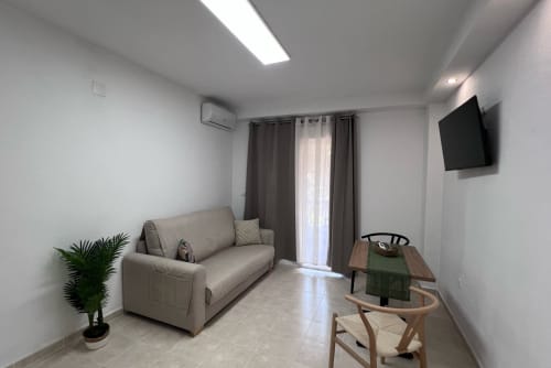Modern living room at Brisa Marina Apartamento 207A in Mazagon with beige sofa, dining table, flat-screen TV, and sea view