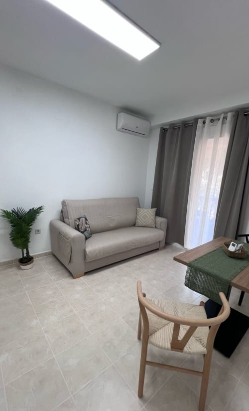 Modern living room at Brisa Marina apartment in Mazagon with beige sofa, wooden chair, sea view balcony, and air conditioning