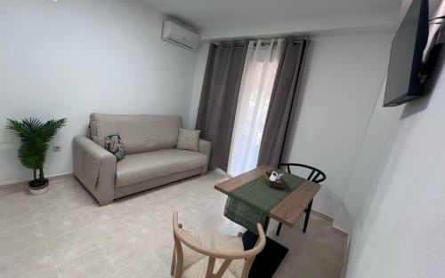 Modern living room with beige sofa, dining table, and sea views at Brisa Marina apartment in Mazagon