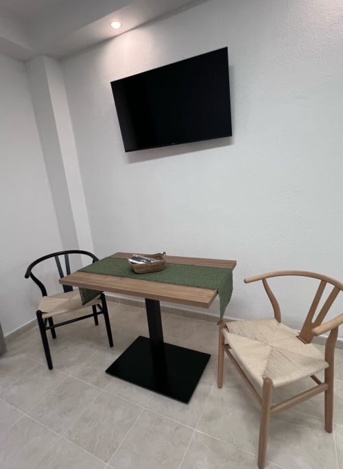 Modern dining area in Brisa Marina Mazagon apartment with wall-mounted TV, wooden table, and designer chairs