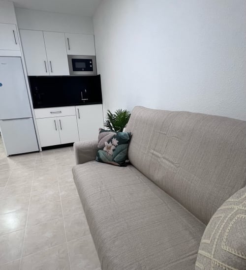 Beige sofa with cushions in open-plan living area of Brisa Marina apartment in Mazagon, modern white kitchen visible behind
