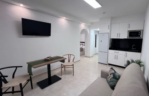 Modern apartment living area with kitchen, dining table, sofa, and wall-mounted TV at Brisa Marina in Mazatán