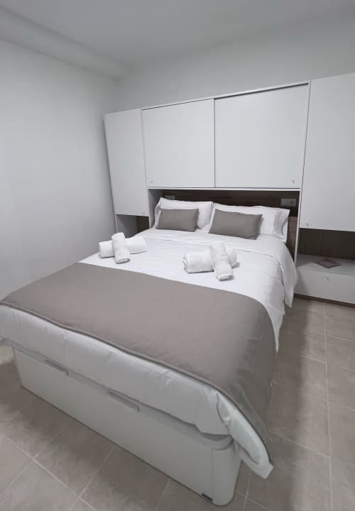 Modern bedroom at Brisa Marina Mazagon apartment with white bedding, gray pillows, and built-in white wardrobes