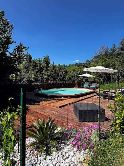 Piscine turquoise avec parasols au gîte Domaine le Manoir à Fossemagne, entourée de jardins
