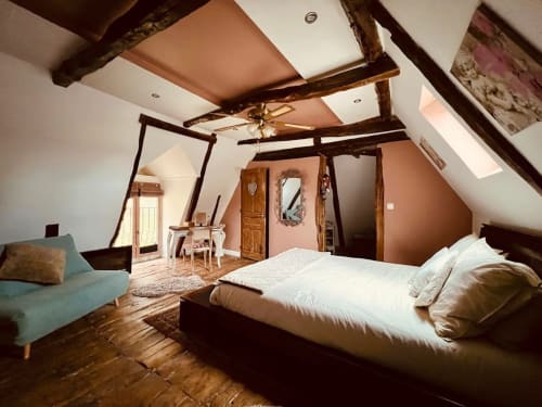 Chambre mansardée élégante du gîte Domaine le Manoir avec poutres apparentes, lit à baldaquin et vue sur le jardin en Périgord Noir