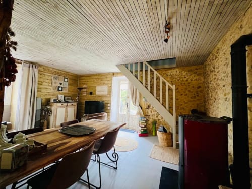 Intérieur rustique du Domaine le Manoir avec murs en bois massif, table à manger, escalier et équipements modernes en Périgord Noir